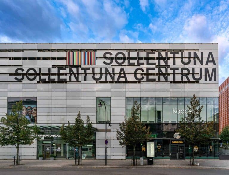Sollentuna Centrum byggnad med skylt och träd framför.