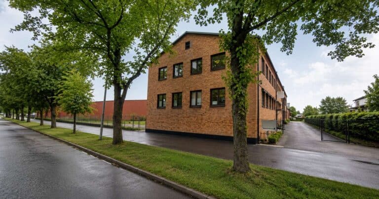 Fasadbild av ett kontorshus i Eskilstuna med träd och väg.
