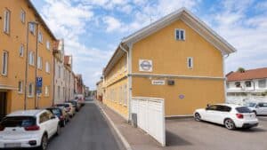 Gatumiljö med parkerade bilar och gul byggnad i Falun.