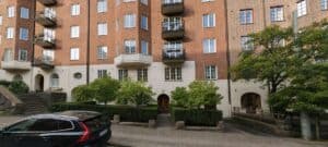 Fasad av ett bostadshus i Göteborg med gröna buskar och träd.