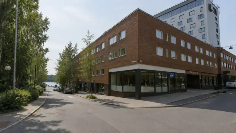 Brun tegelfastighet i hörnet av gatan i Umeå med lokal i gatuplan.