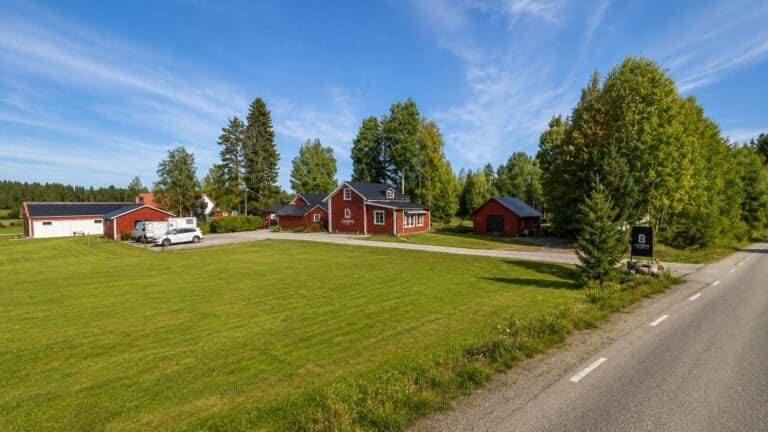 Landsby med röda hus och grönt gräs under blå himmel i Piteå.