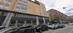 Fasad av flerbostadshus i Hammarby Sjöstad med parkerade bilar framför.