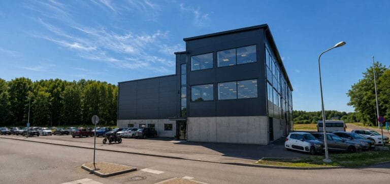 Modern kontorsbyggnad i Huddinge med stora fönster och parkeringsplats.