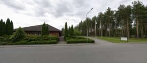 Landskapsbild av en byggnad omgiven av träd och buskar i Katrineholm.
