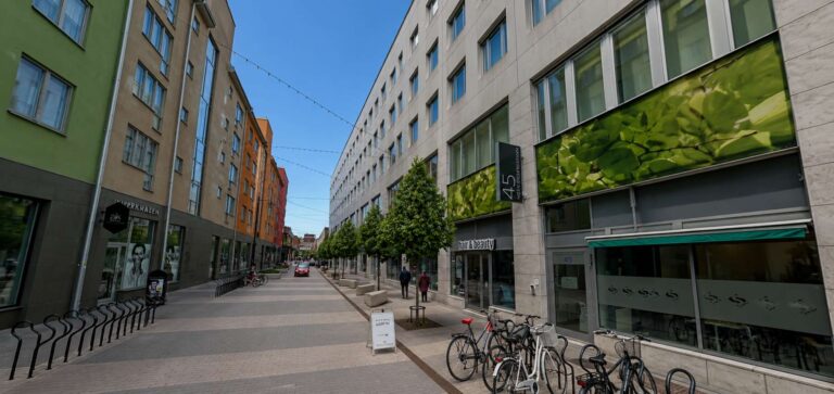 Gatumiljö med moderna byggnader och cyklar vid trottoaren.
