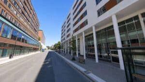 Modern city street with tall buildings and clear blue sky.