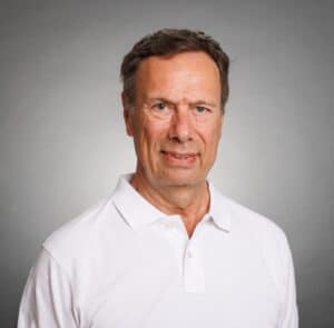 Man i vit polo shirt mot neutral bakgrund.