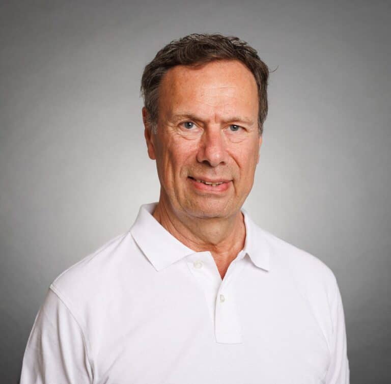 Man i vit polo shirt mot neutral bakgrund.