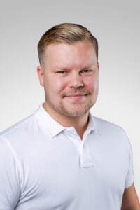 Porträtt av man i vit polo mot ljus bakgrund.