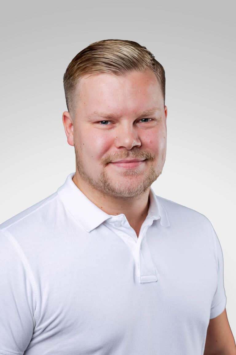 Porträtt av man i vit polo mot ljus bakgrund.