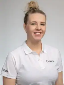 Kvinna i vit Limbraklänning med uppsatt hår ler mot kameran.