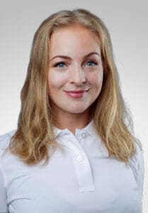 Ung kvinna med blont hår och vit skjorta, leende mot kameran.