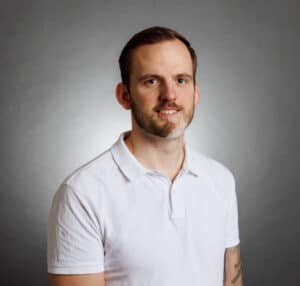 Porträtt av Hampus Nordenström i vitt polo mot grå bakgrund.