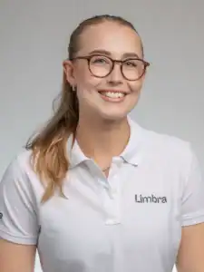 Kvinna i vit Limba-tröja och glasögon ler mot kameran.