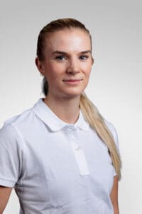 Kvinna i vit polo mot ljusgrå bakgrund.
