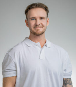 Man i vit polo shirt med lätt leende mot kameran.