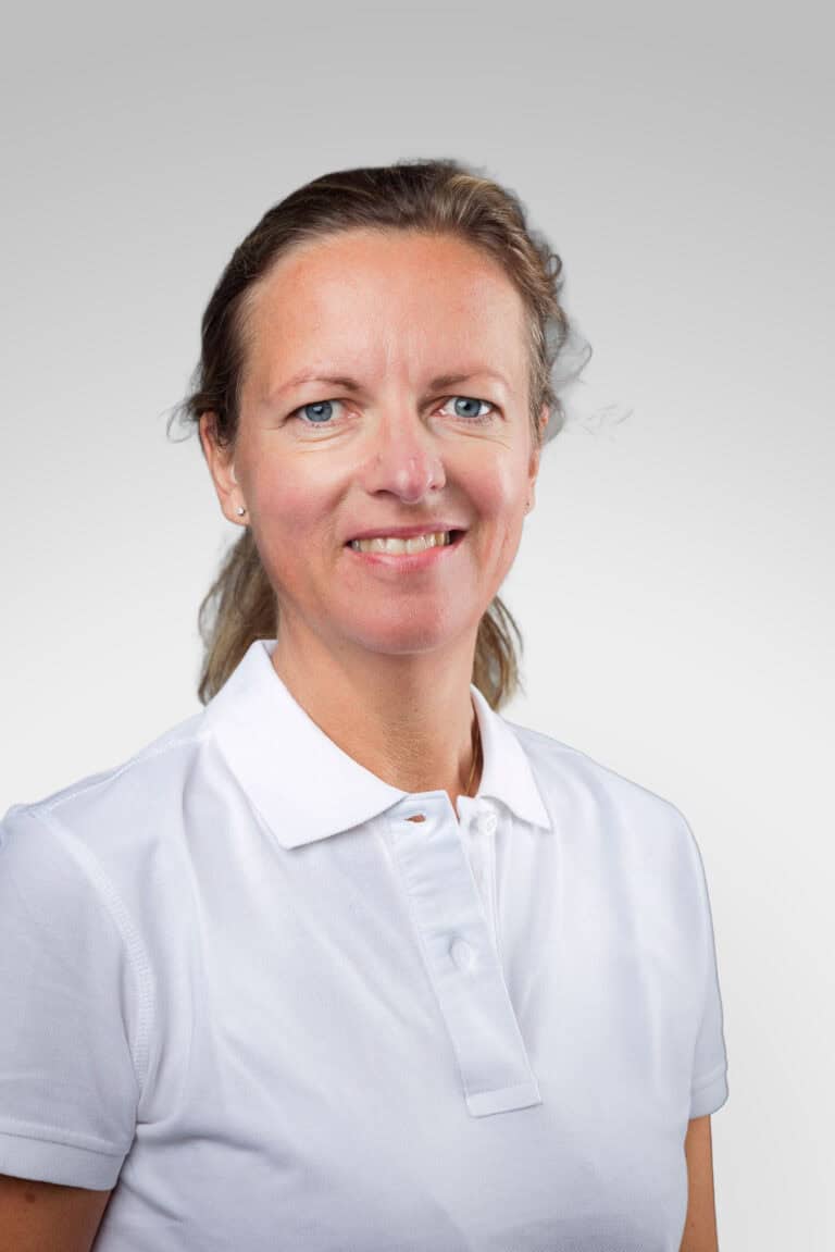 Kvinna i vit polo mot ljusgrå bakgrund.
