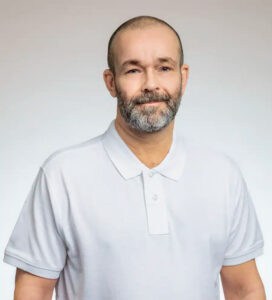 Kjell Gottling, kiropraktor, i vitt labbskjorta, ler mot kameran.