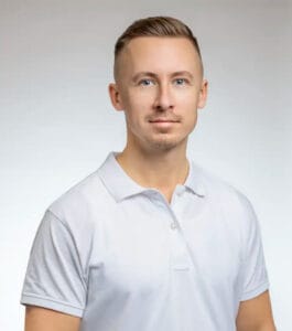 Man i vit polo shirt mot ljusgrå bakgrund.