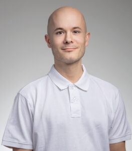 Man i vit polo shirt med neutral bakgrund.
