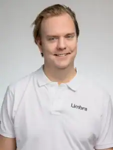 Man i vit Limbraklänning ler mot kameran.