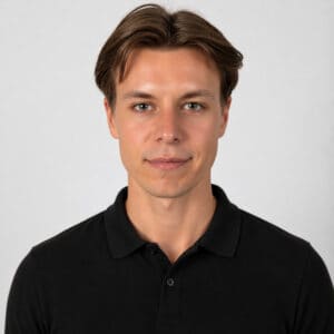 Ung man i svart polo mot ljus bakgrund.