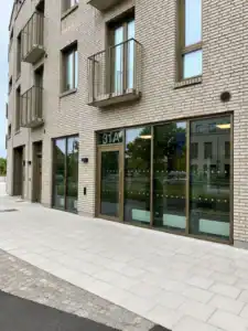 Ljus tegelbyggnad med glasparti i gatuplan i Bjärred.