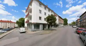 Vitt flerbostadshus med balkonger och lokal i gatuplan i Sandviken.