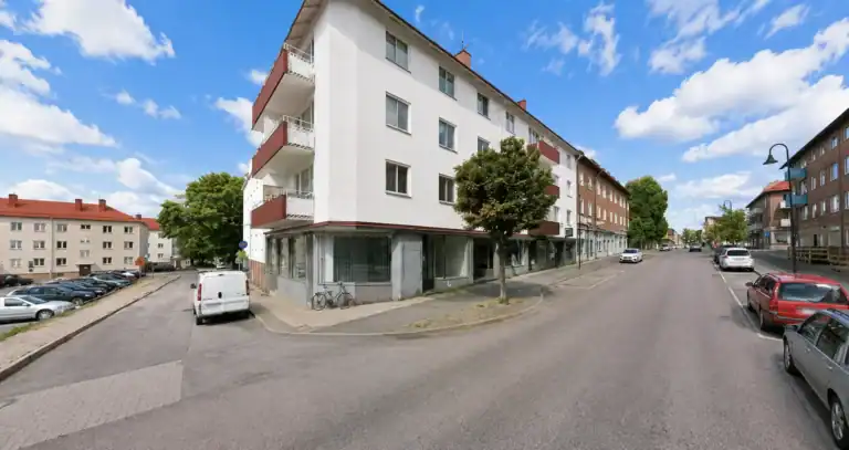 Vitt flerbostadshus med balkonger och lokal i gatuplan i Sandviken.
