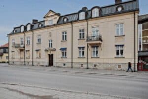 Ljus putsad byggnad i klassisk stil längs gatan i Västerås.