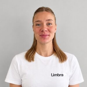 Kvinna med blont hår och vit Limbratröja som ler.