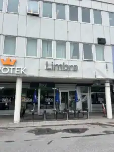 Limbra klinikbyggnad med uteservering och parasoller.
