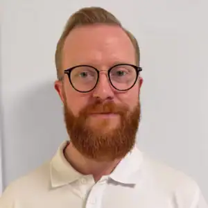 Porträtt av Jesper Åhlberg Thörn med glasögon och röd skägg.