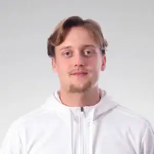 Ung man med ljusbrunt hår och lätt skägg, bär vit hoodie.