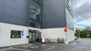 Modern klinikbyggnad med cyklar utanför och parkeringsplats.