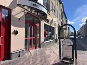 Limbra klinikens entré med skylt och cykelställ på trottoaren.