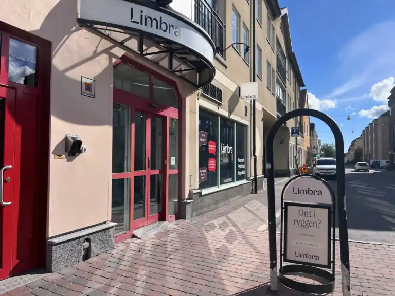 Limbra klinikens entré med skylt och cykelställ på trottoaren.