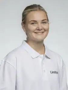Glad kvinna i vit arbetsuniform med Limbra-logga.