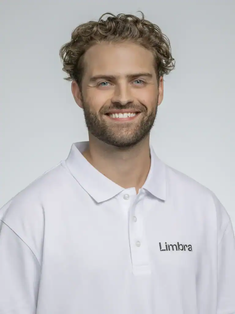 Glad man i vit Limbra-tröja med lockigt hår och skägg.