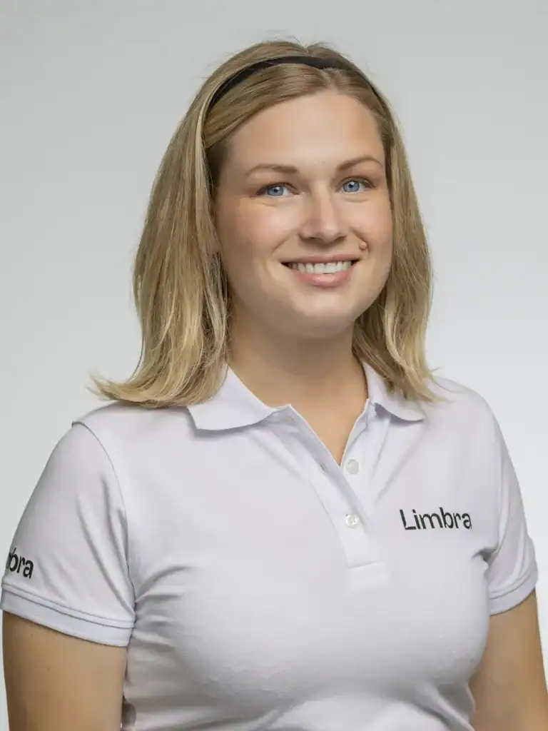 Kvinna i vit Limbra-uniform med leende och blont hår.