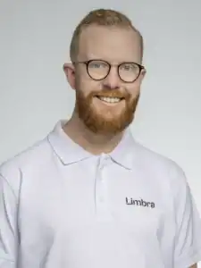 Glad man med glasögon och skägg i vit klinikuniform.
