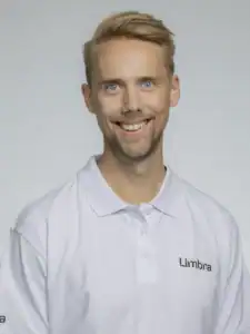 Glad man i vit klinikuniform med Limbra-logga.