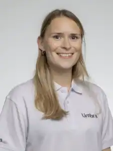 Kvinna med långt blont hår och vit Limbra-tröja, ler mot kameran.