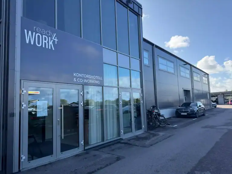 Modern kontorsbyggnad med glasfasad och cyklar utanför.