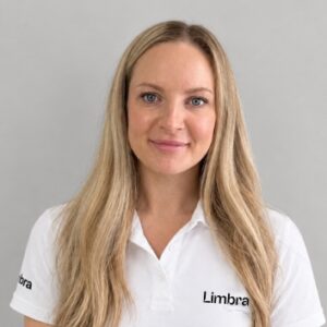 Kvinna med långt blont hår i Limbrakläder som ler.
