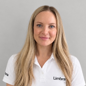 Kvinna med långt blont hår i Limbrakläder som ler.